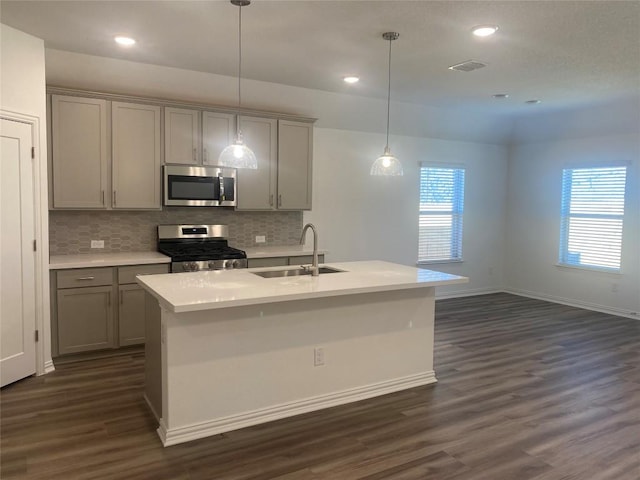 kitchen featuring a sink, backsplash, appliances with stainless steel finishes, and gray cabinetry