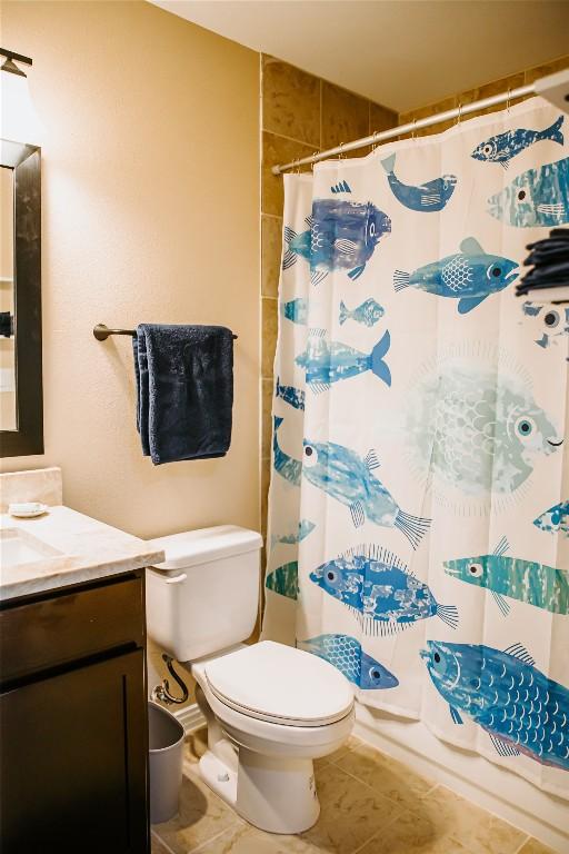 bathroom featuring curtained shower, toilet, vanity, and tile patterned flooring