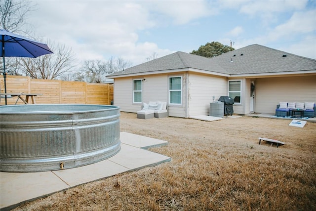 rear view of house featuring a patio area, a shingled roof, and fence