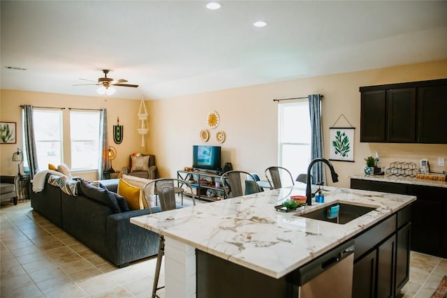 kitchen with visible vents, a sink, open floor plan, a breakfast bar area, and stainless steel dishwasher