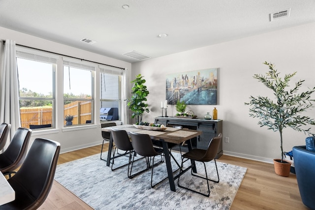 dining space with visible vents, light wood-type flooring, and baseboards