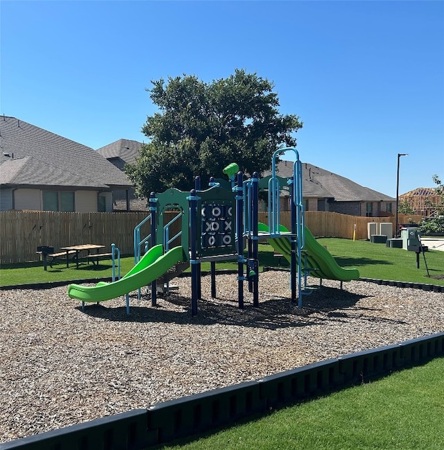 community jungle gym featuring a lawn and fence