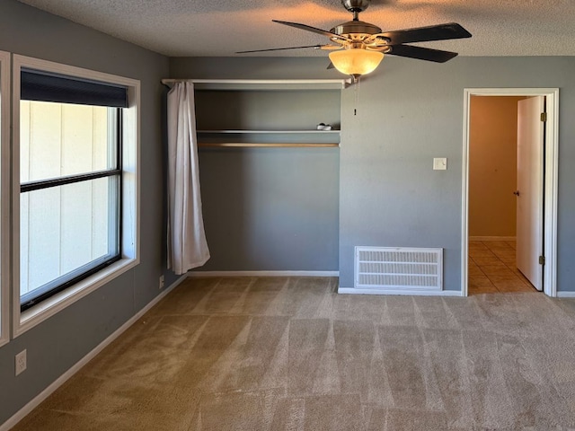 unfurnished bedroom with visible vents, multiple windows, a textured ceiling, and carpet floors