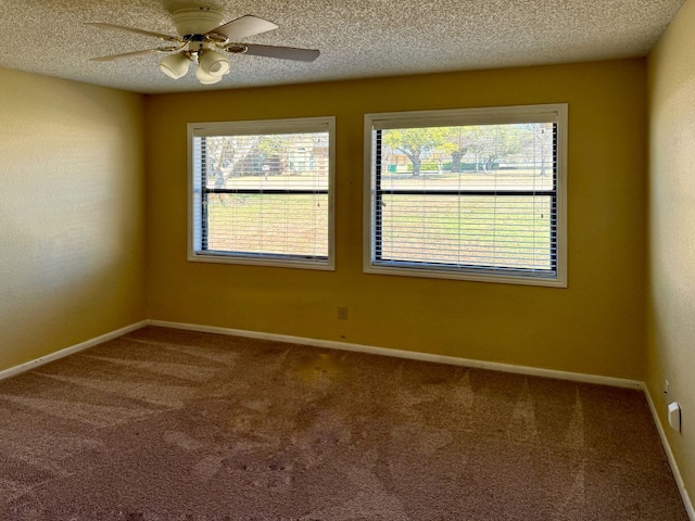 carpeted spare room featuring plenty of natural light, a textured ceiling, baseboards, and a ceiling fan