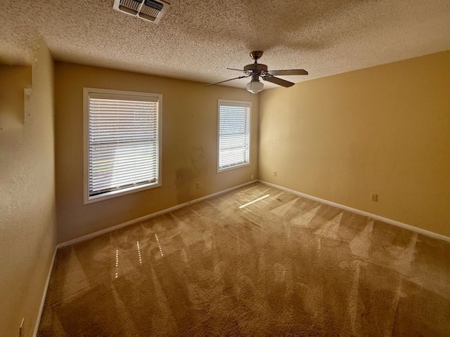 unfurnished room featuring visible vents, baseboards, ceiling fan, a textured ceiling, and light colored carpet