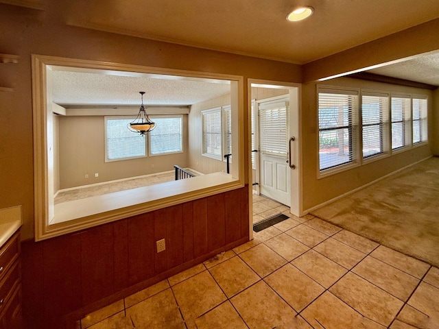 kitchen with a wealth of natural light, light tile patterned floors, light colored carpet, and a textured ceiling