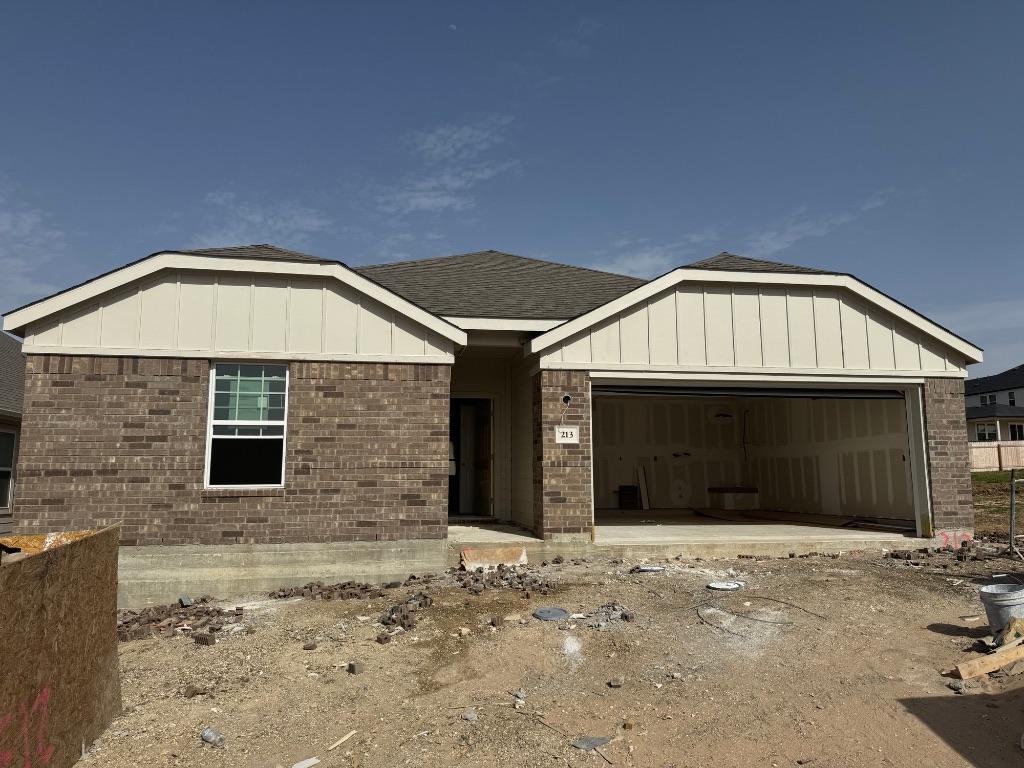 view of front of house with board and batten siding, a garage, and brick siding