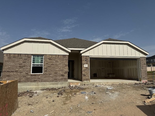 view of front of house with board and batten siding, a garage, and brick siding