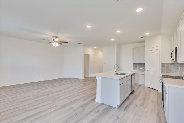 213 Seattle Slew Dr, Jarrell, TX 76537 - kitchen with a sink, appliances with stainless steel finishes, a kitchen island with sink, a ceiling fan, and light wood-type flooring