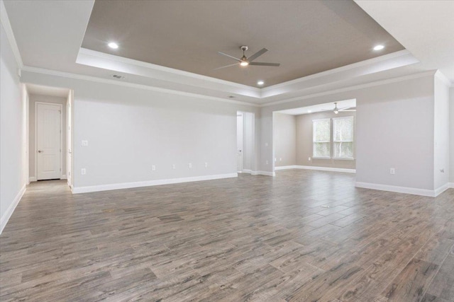 unfurnished room with a tray ceiling, baseboards, and wood finished floors