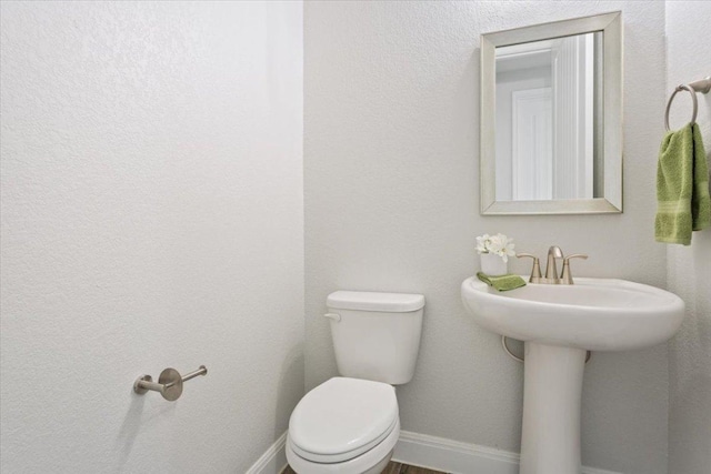 half bath with toilet and baseboards