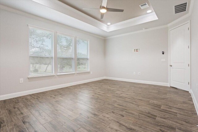 unfurnished room featuring visible vents, a tray ceiling, and wood finished floors