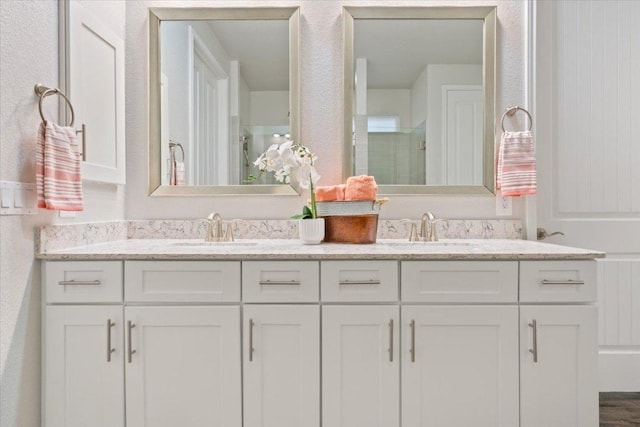 full bathroom with double vanity, a stall shower, and a sink