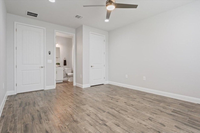 unfurnished bedroom featuring visible vents, connected bathroom, baseboards, and wood finished floors