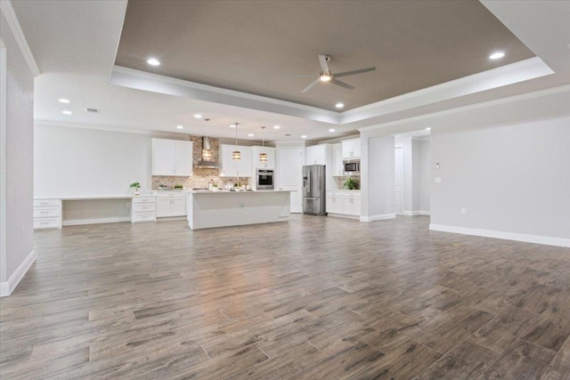 unfurnished living room with a raised ceiling, a ceiling fan, dark wood finished floors, crown molding, and baseboards