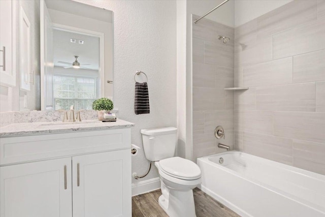 bathroom featuring toilet, wood finished floors, washtub / shower combination, vanity, and a textured wall