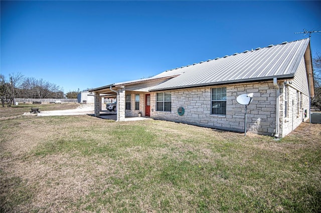 rear view of house with stone siding, a lawn, metal roof, and a patio