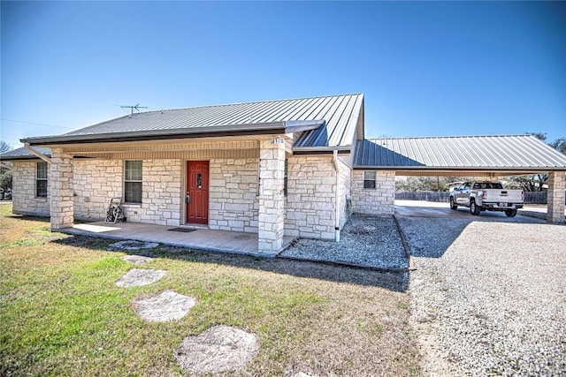 view of front of house featuring a carport, a front lawn, driveway, and metal roof