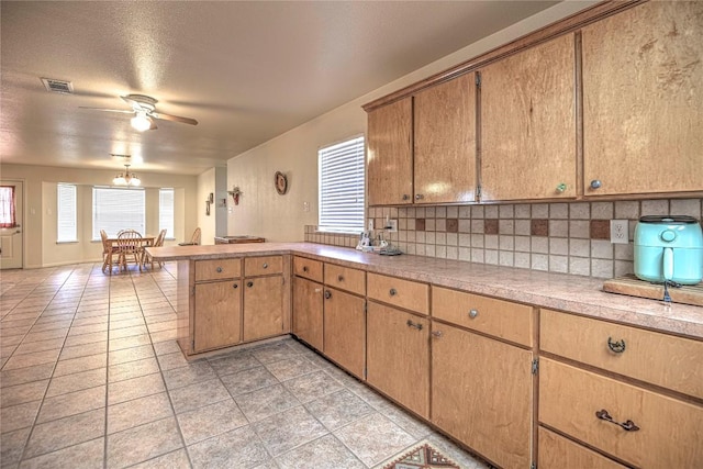 kitchen featuring a peninsula, light countertops, visible vents, and backsplash