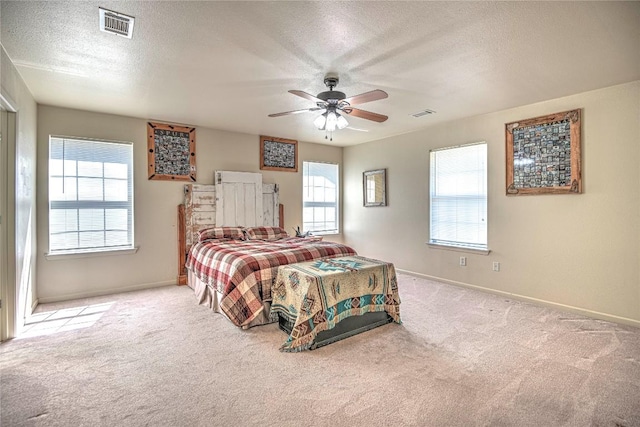 carpeted bedroom featuring ceiling fan, baseboards, visible vents, and a textured ceiling