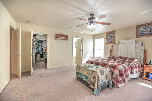 bedroom featuring visible vents, a walk in closet, a ceiling fan, a textured ceiling, and carpet floors