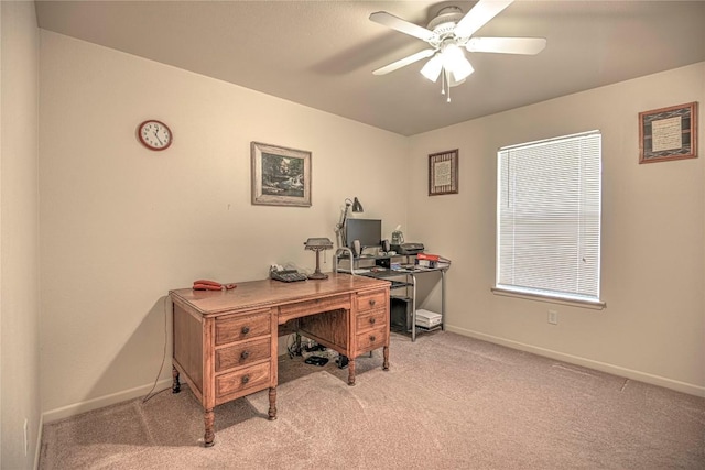 office area featuring ceiling fan, baseboards, and light carpet