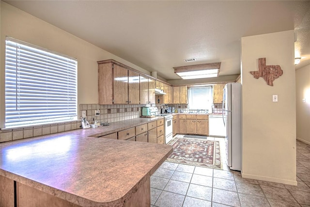 kitchen featuring visible vents, under cabinet range hood, backsplash, white appliances, and a peninsula