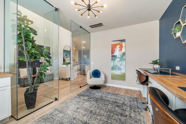 office space with visible vents, baseboards, a chandelier, and light wood finished floors