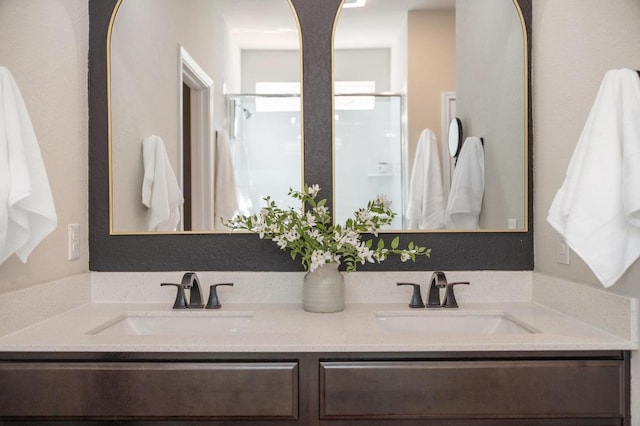 full bathroom featuring double vanity, an enclosed shower, and a sink