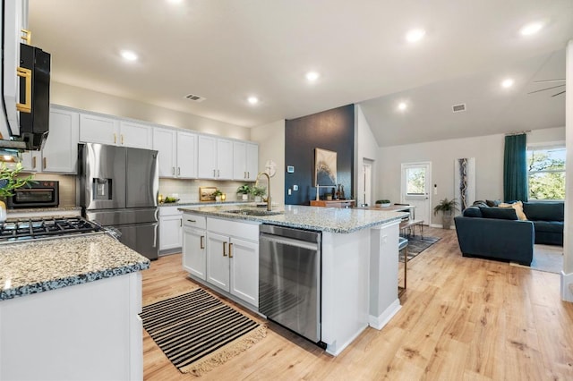 kitchen featuring visible vents, a sink, white cabinets, appliances with stainless steel finishes, and open floor plan