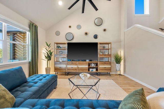 living room with a ceiling fan, wood finished floors, baseboards, and high vaulted ceiling