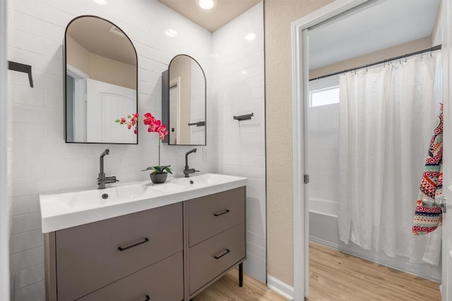 bathroom with a sink, tile walls, wood finished floors, and double vanity