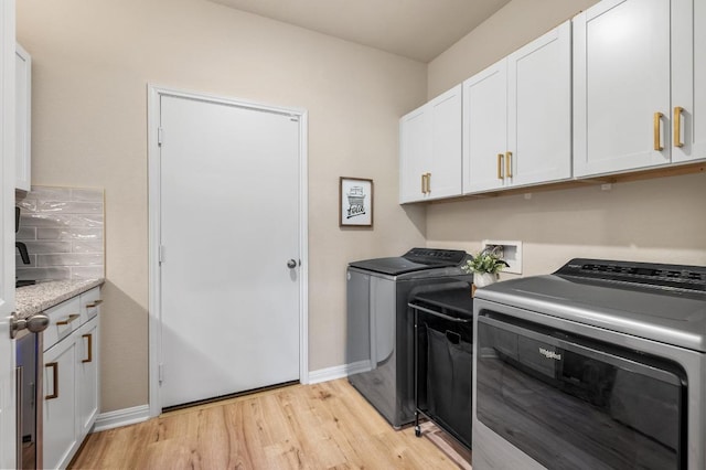 washroom with light wood finished floors, cabinet space, baseboards, and separate washer and dryer