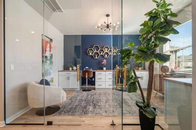 interior space featuring visible vents, built in study area, an inviting chandelier, and wood finished floors