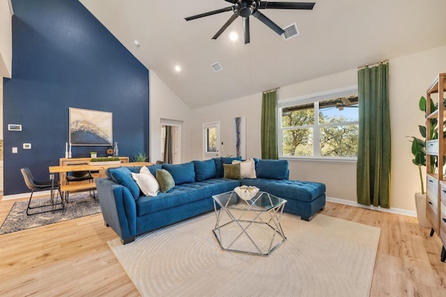 living room with visible vents, high vaulted ceiling, and wood finished floors