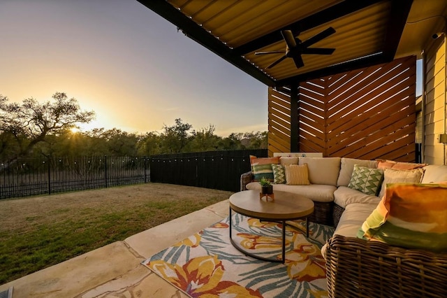 patio terrace at dusk with a yard, an outdoor living space, a fenced backyard, and ceiling fan