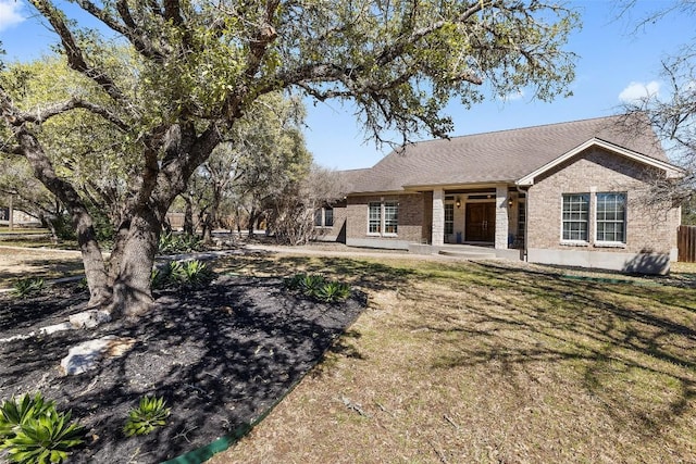 back of house featuring a lawn and brick siding