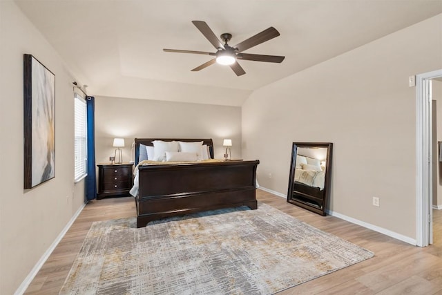 bedroom featuring light wood-style flooring, a ceiling fan, baseboards, and vaulted ceiling