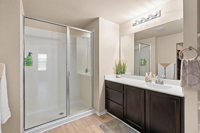 bathroom featuring vanity, wood finished floors, a stall shower, and a textured ceiling