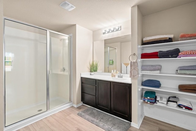 bathroom featuring visible vents, a shower stall, baseboards, wood finished floors, and vanity