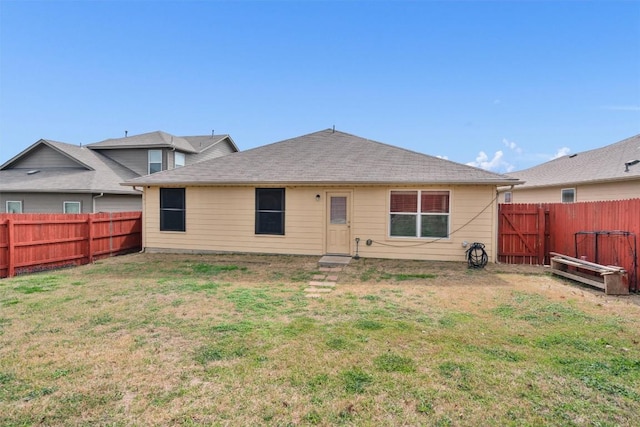 rear view of house with a lawn, a fenced backyard, and a shingled roof