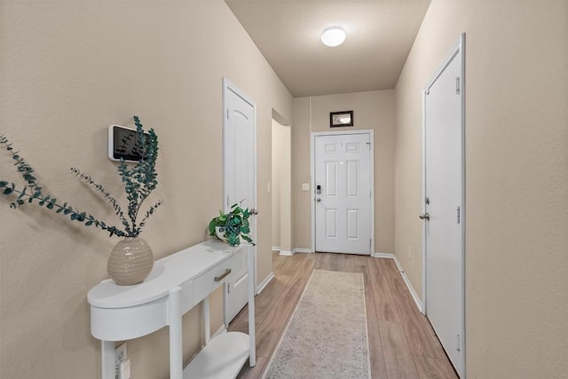 doorway featuring light wood-style flooring and baseboards