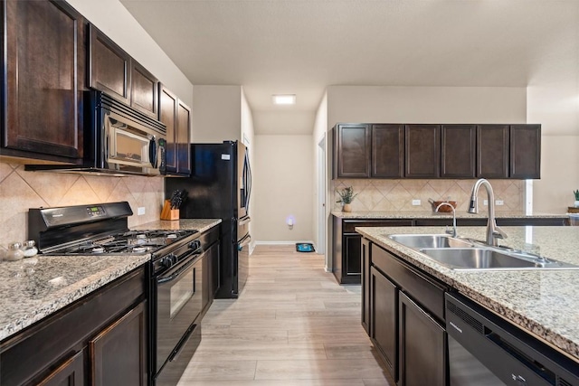 kitchen with black appliances, light wood-type flooring, dark brown cabinetry, and a sink