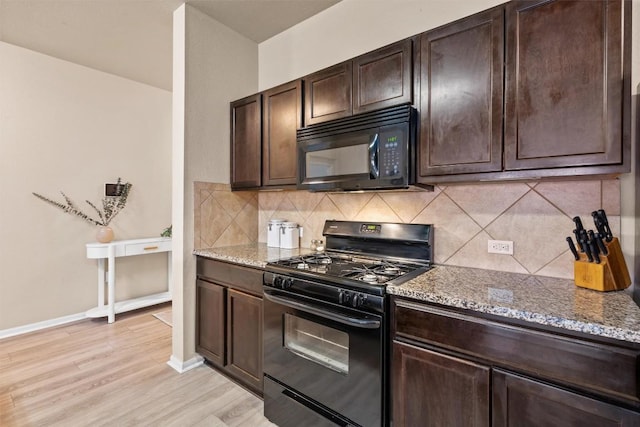 kitchen with light stone counters, dark brown cabinetry, black appliances, and light wood finished floors