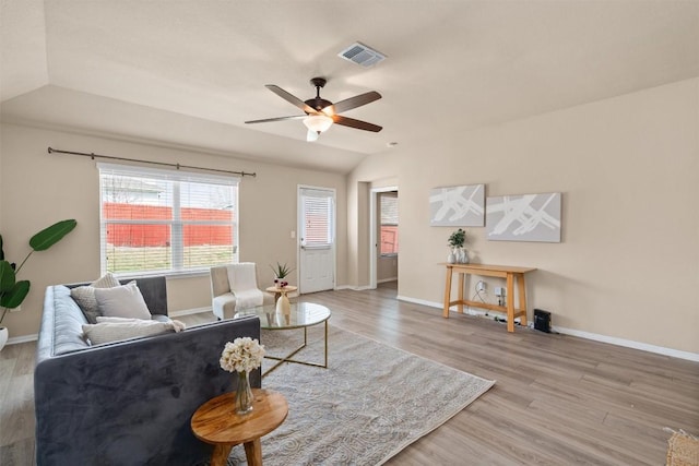 living room featuring vaulted ceiling, wood finished floors, visible vents, and baseboards