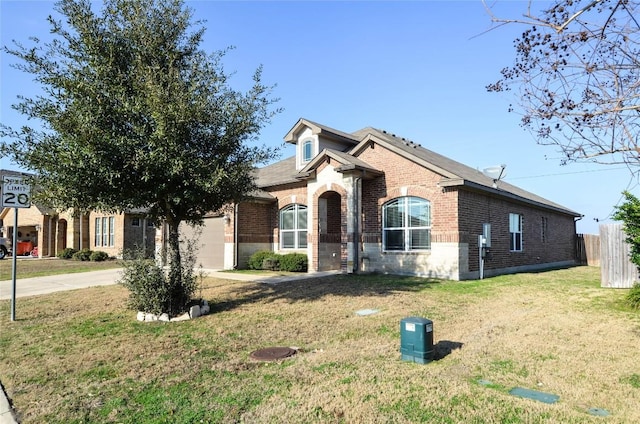 view of front of property with brick siding, an attached garage, fence, a front yard, and driveway