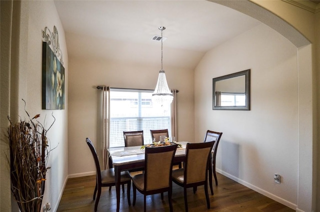 dining room featuring lofted ceiling, arched walkways, dark wood-style flooring, and baseboards