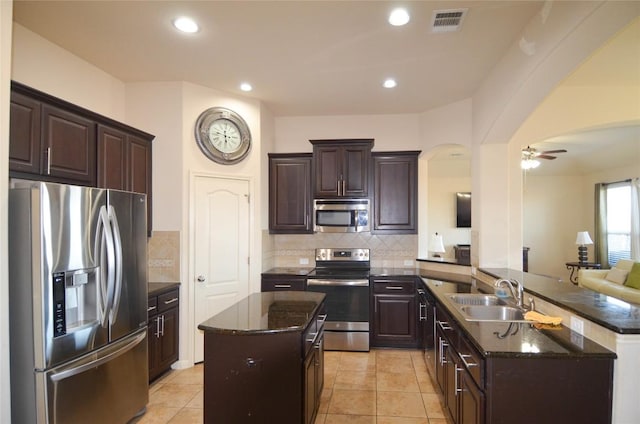 kitchen featuring visible vents, a sink, stainless steel appliances, arched walkways, and a peninsula