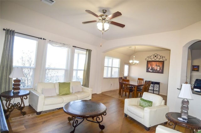 living room with wood finished floors, visible vents, and arched walkways