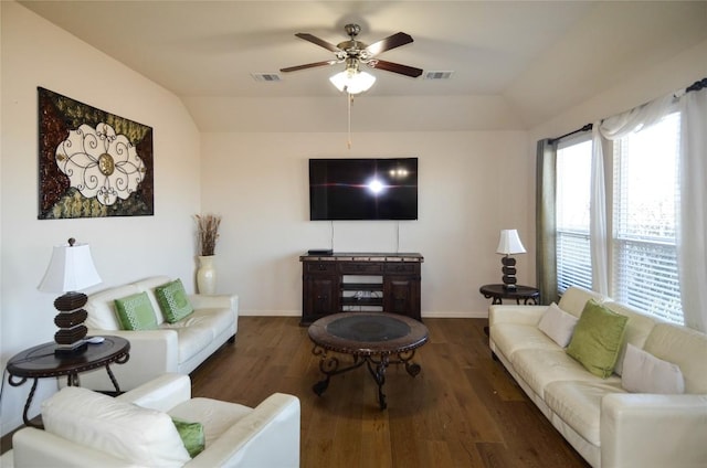 living room featuring vaulted ceiling, visible vents, baseboards, and wood finished floors